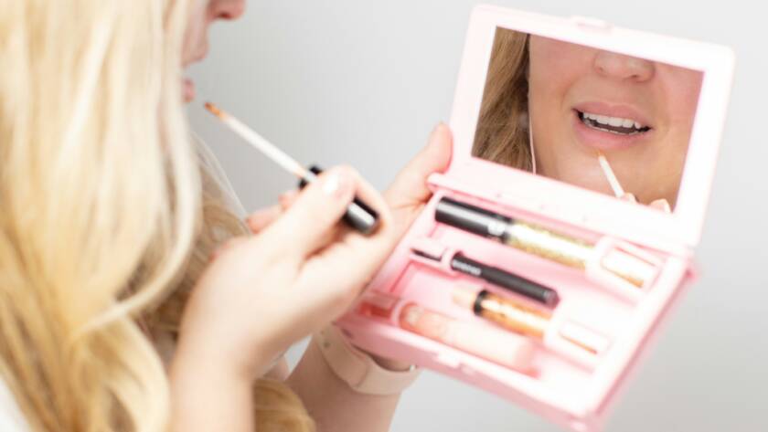 A girl doing make up in tiny mirror.